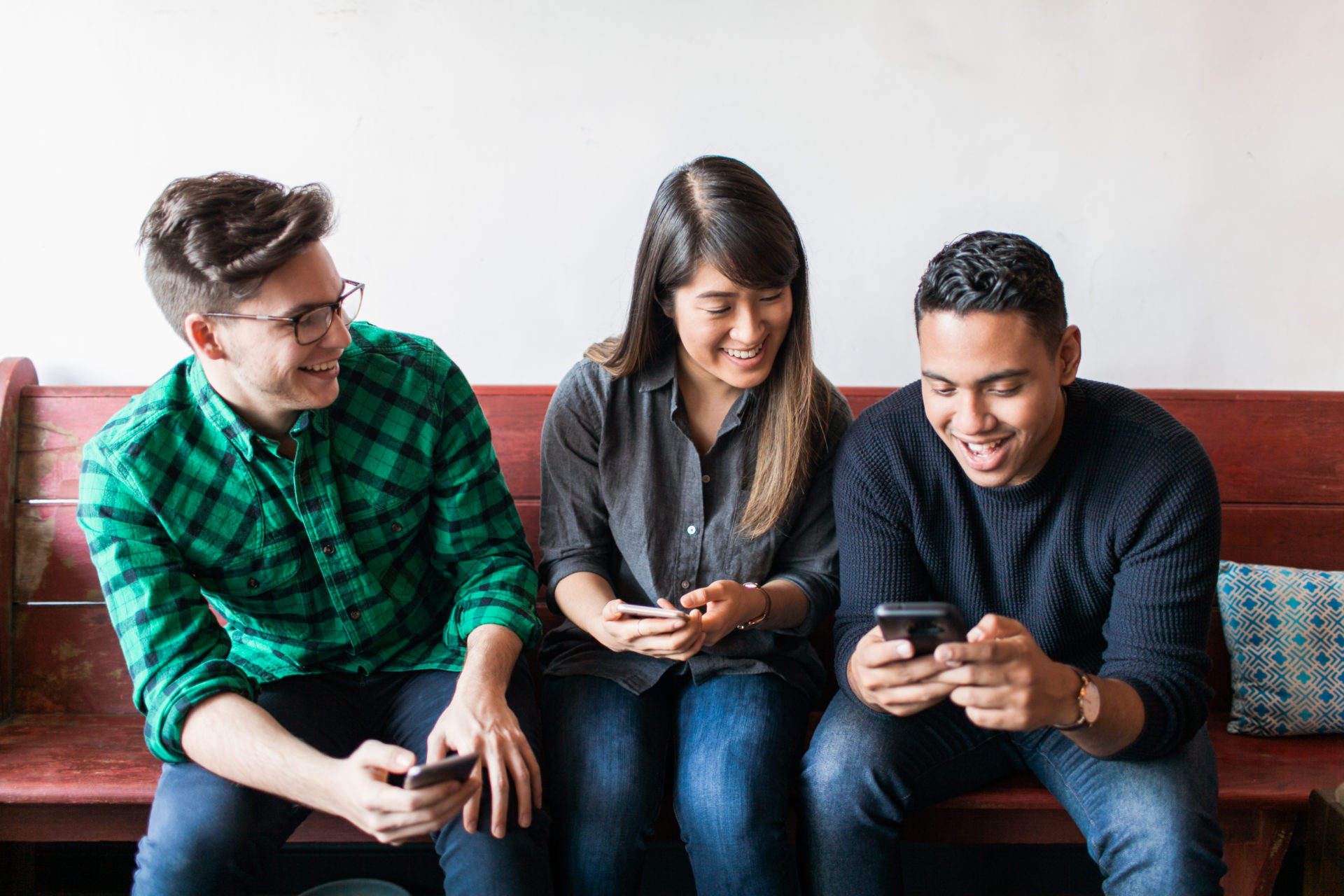 Three millennials all holding and looking at their cellphones