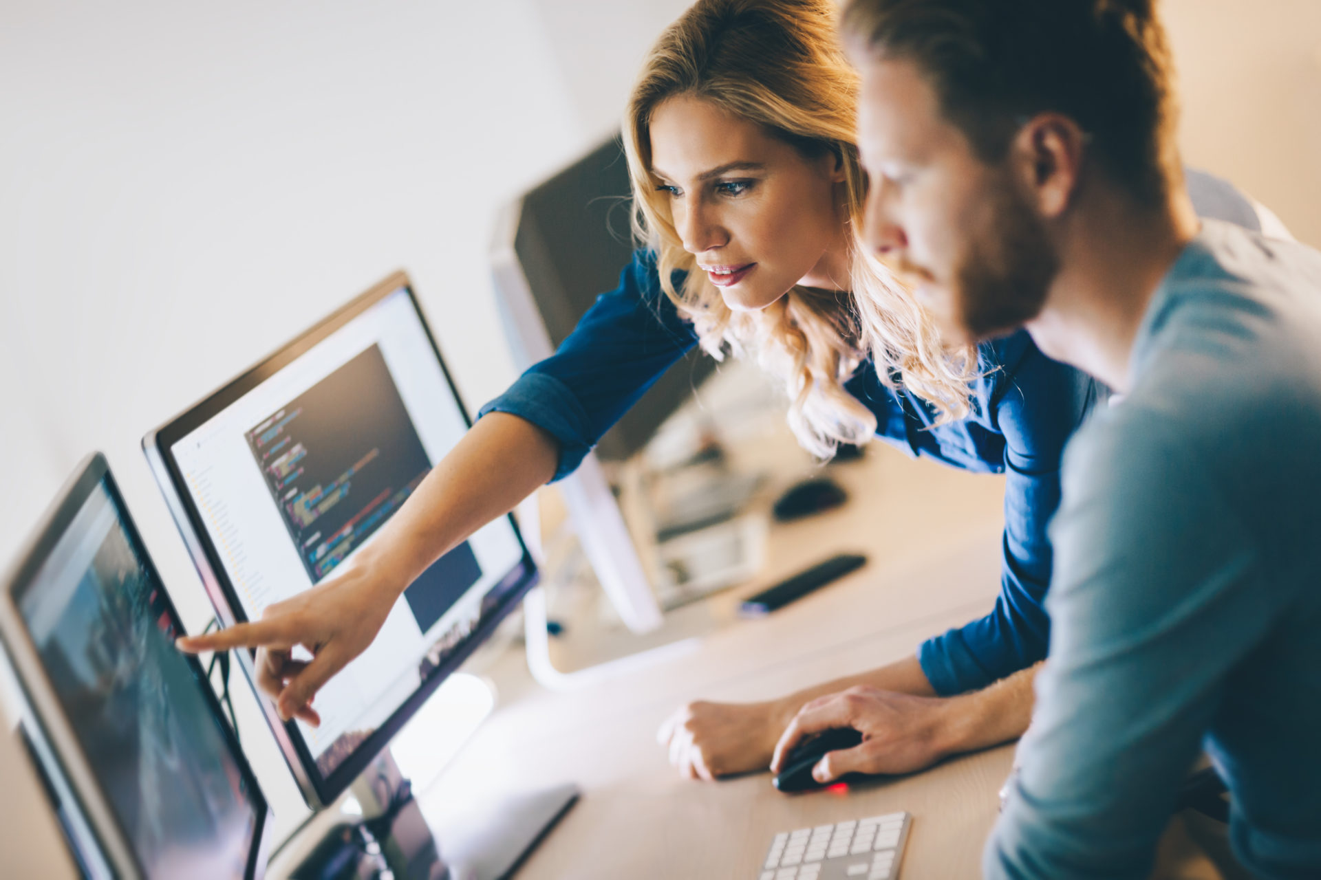 Two professionals looking at a computer and pointing at the screen