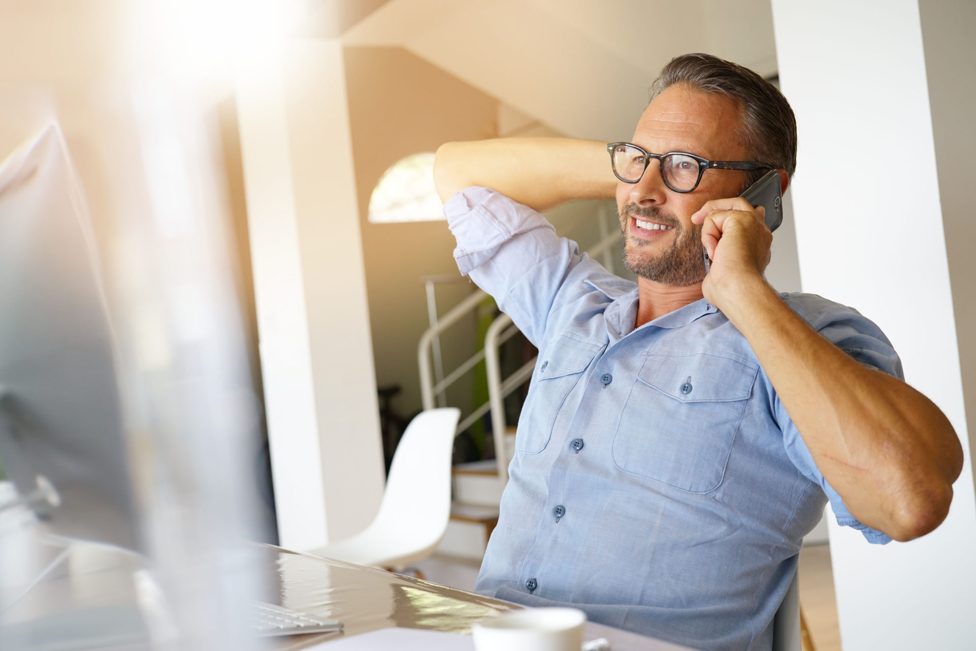 Male professional leaning back in his chair as he talks on his cellphone