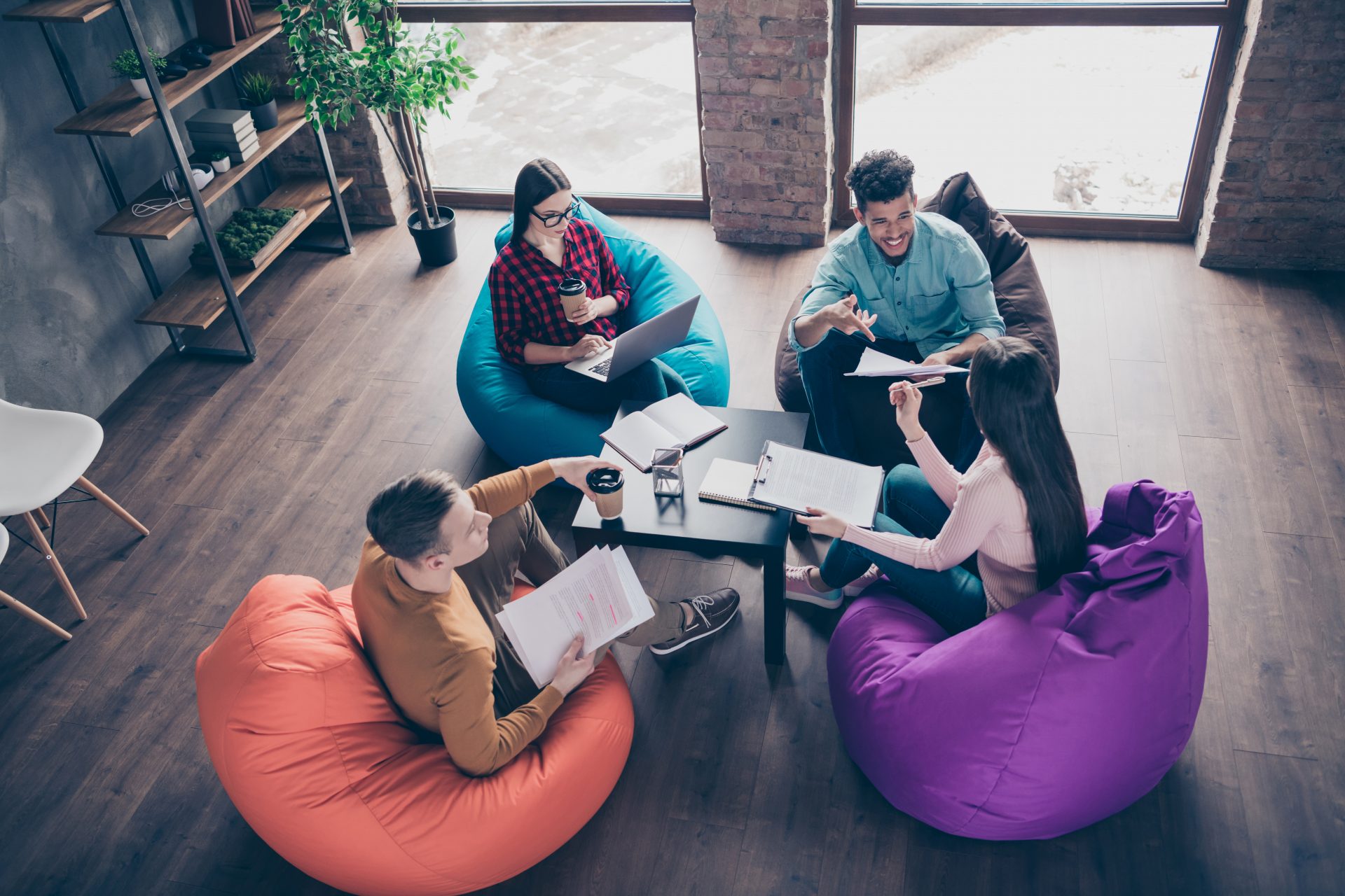 Four professionals sitting in beanbags as they work