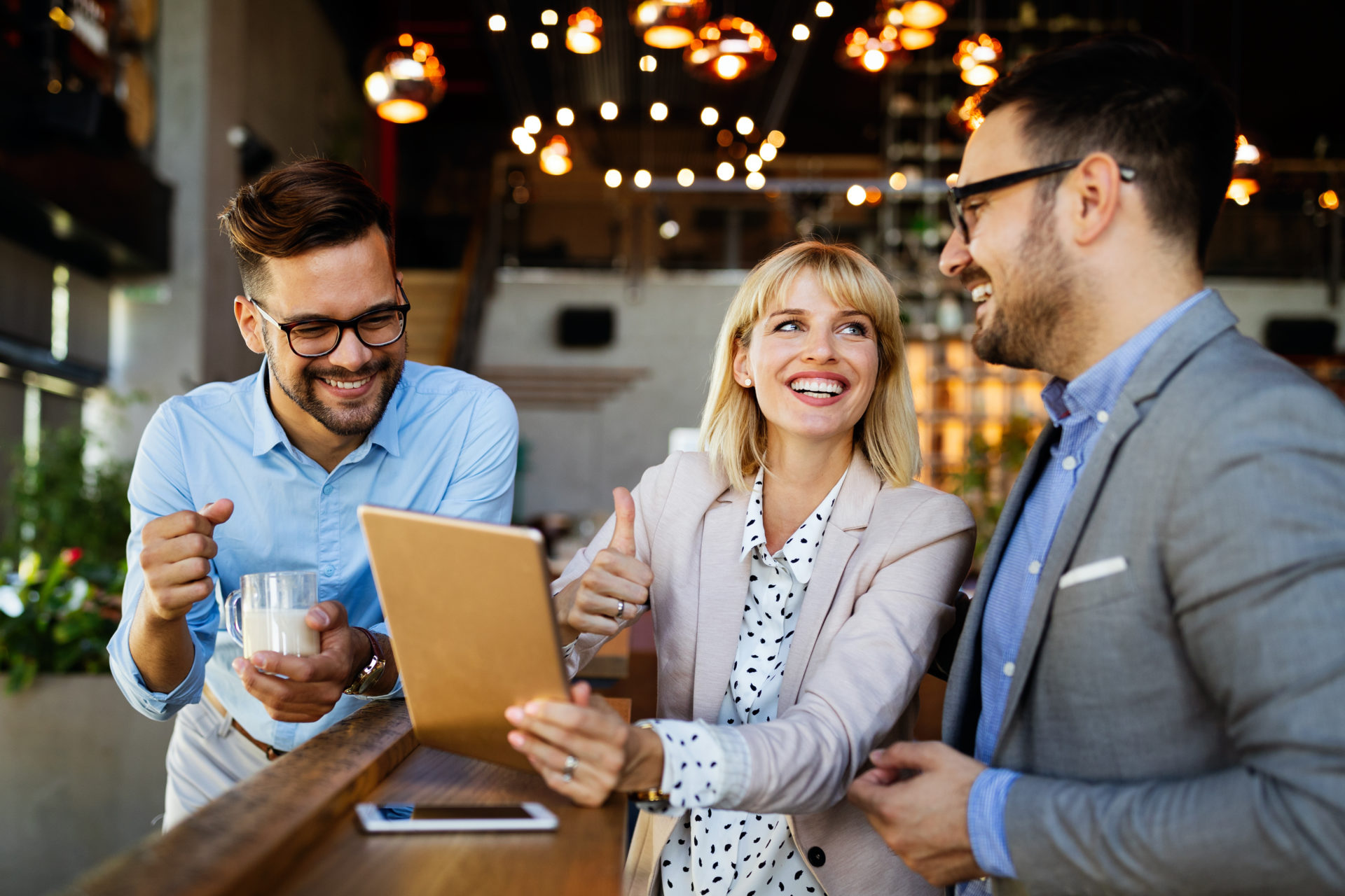 Three professionals laughing while holding an iPad