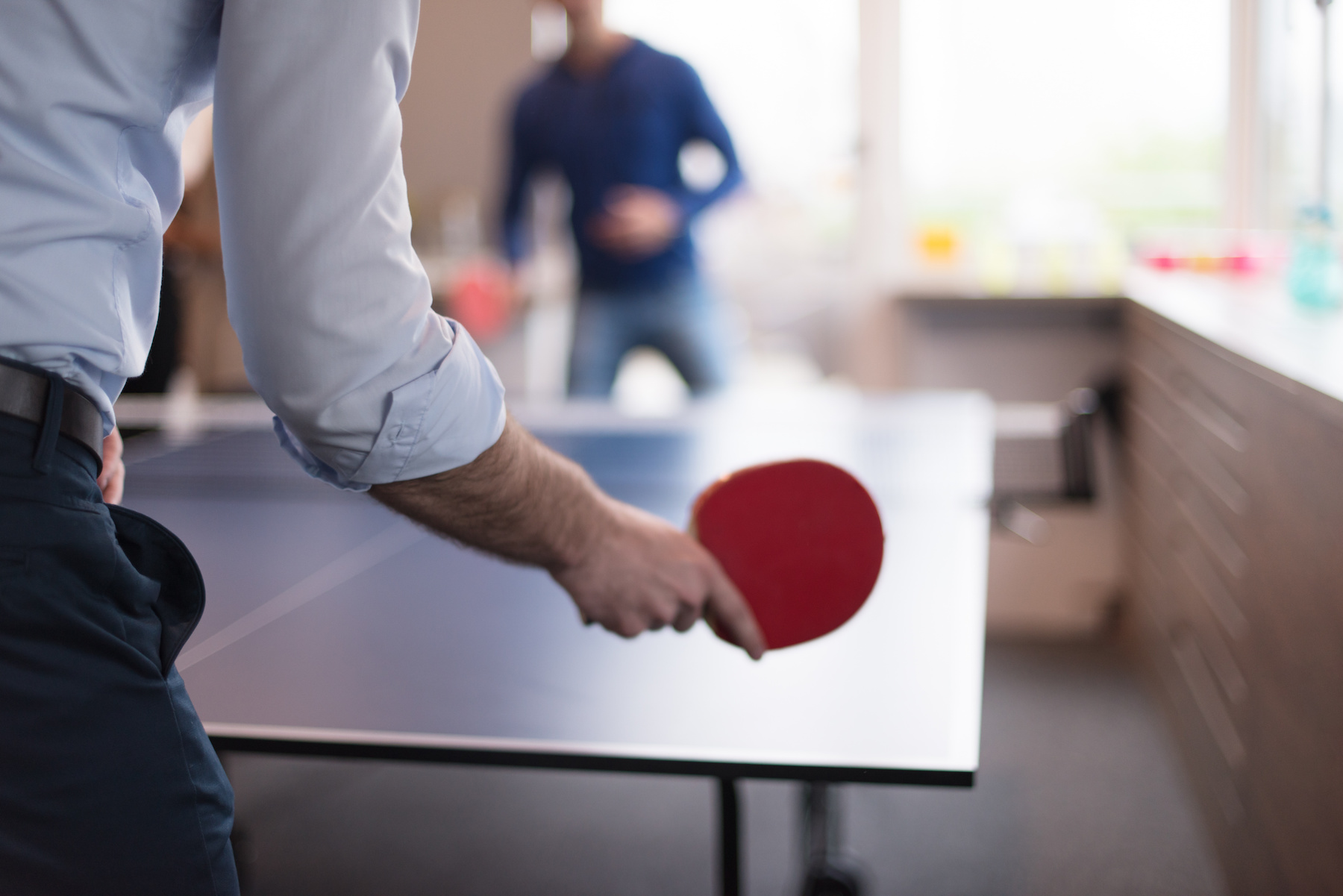 Two professionals playing ping pong in their office