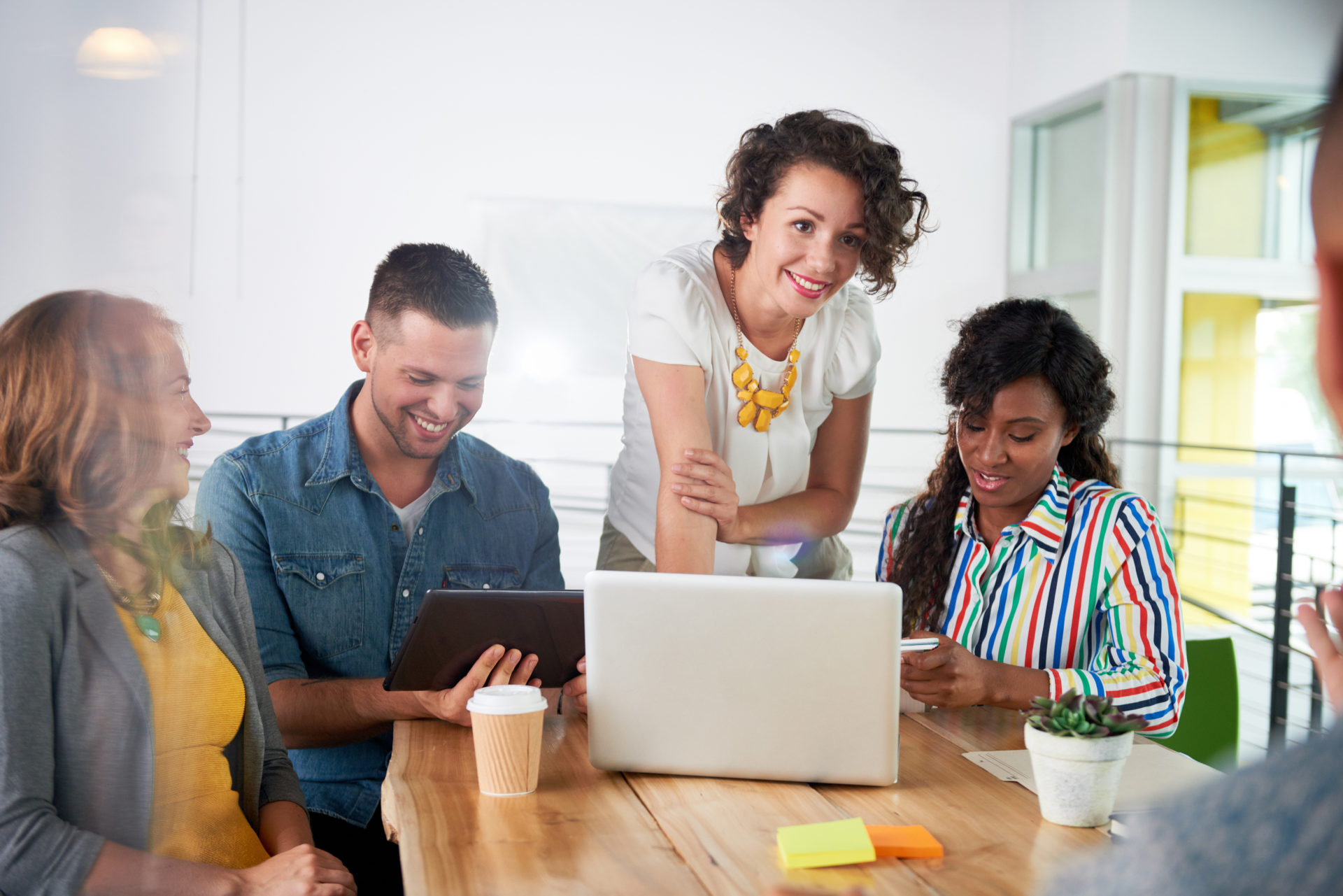 Four professionals gathered at a table looking at an iPad and taking notes