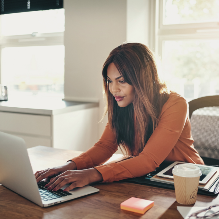 Young female professional working online with a laptop while sitting at a desk in her home office