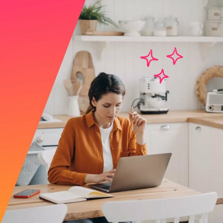 Female freelancer on her laptop next to a notepad at a table in her kitchen