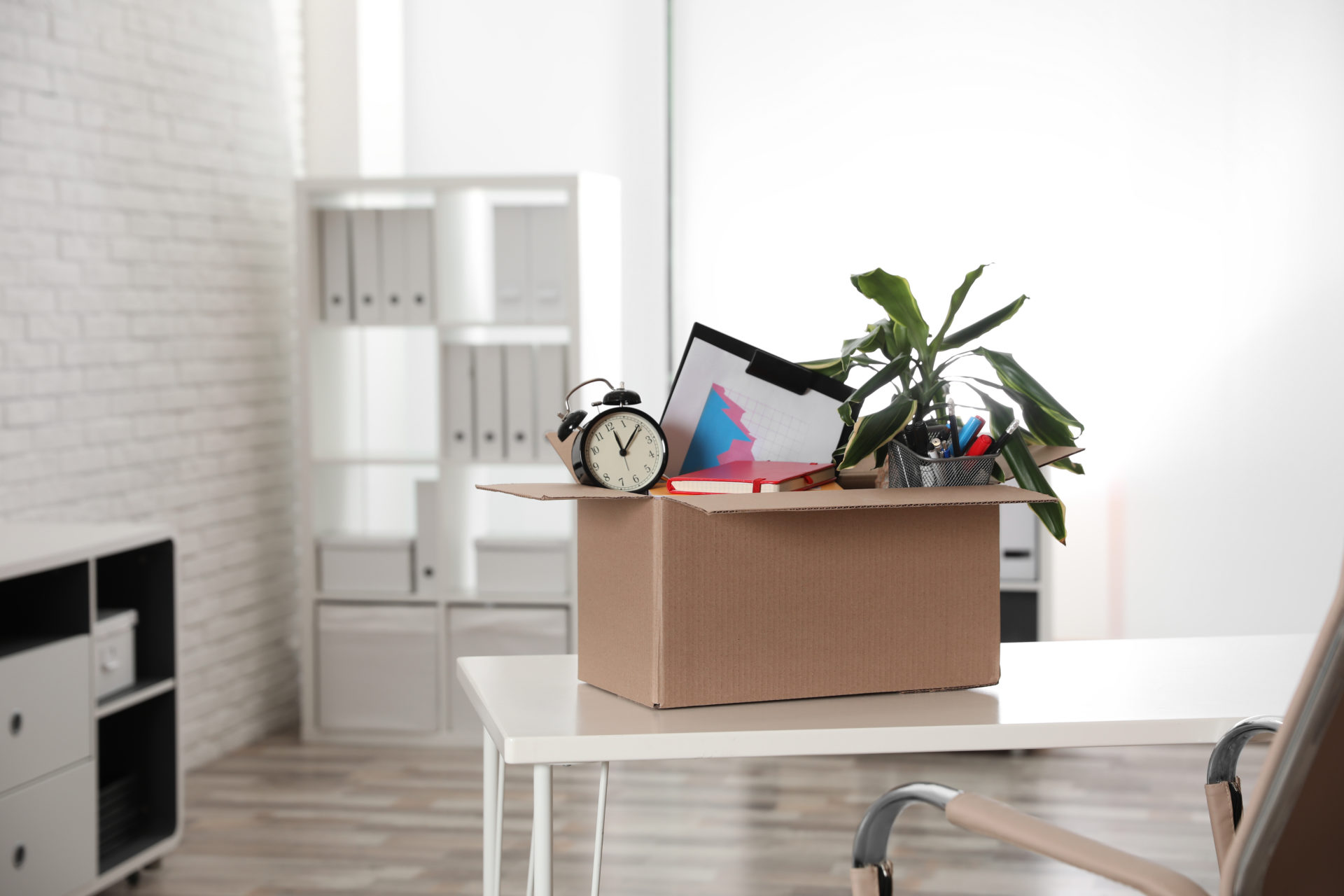 Cardboard box full of employee's stuff on table in office after quiet firing