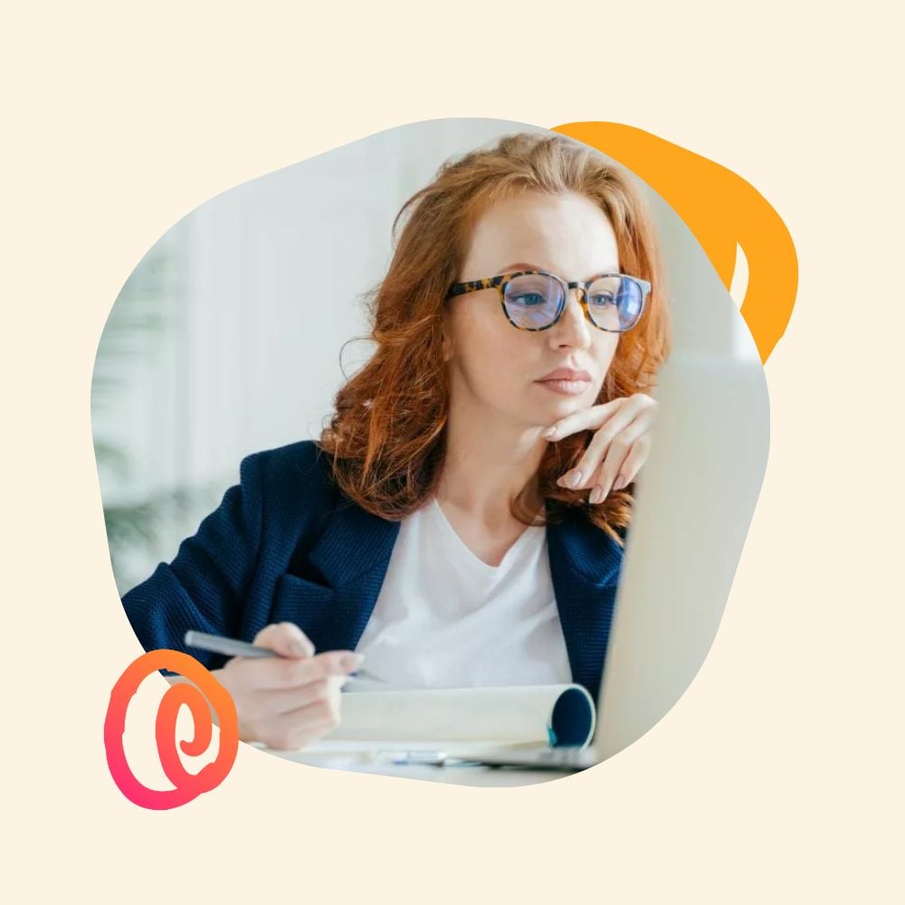 Serious female employee at her desk with her laptop open taking notes on how to prepare for a recession