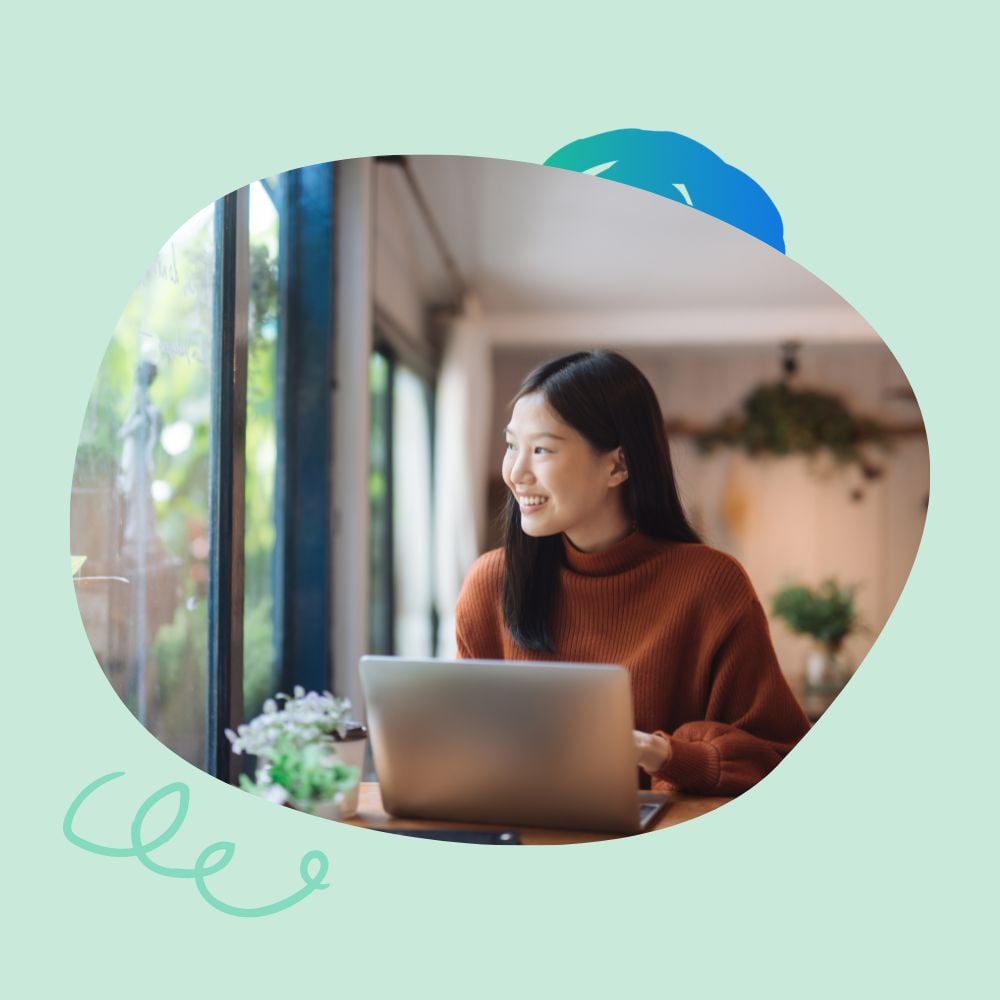 Happy young woman freelancer working at a coffee shop with a laptop focusing on improving her skills