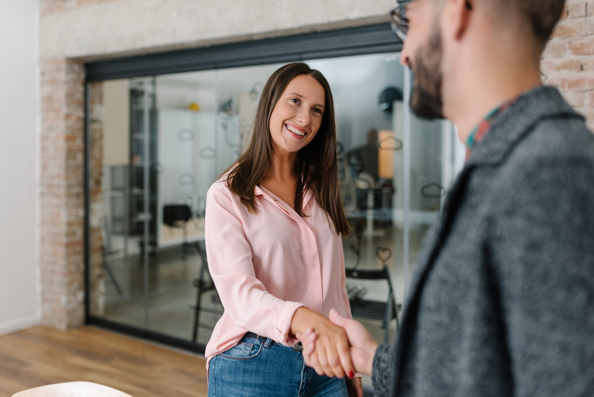 Hiring manager shaking student's hand standing up in an office before internship interview