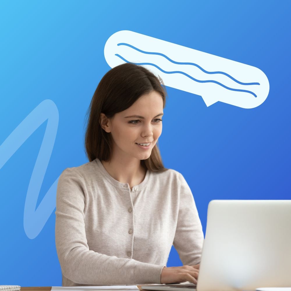 Young woman sitting at a desk, smiling and looking at a laptop screen with a thought bubble above her head