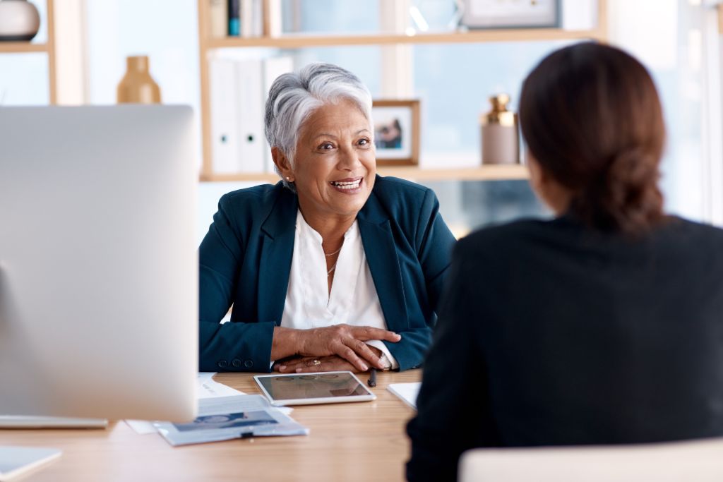 HR manager and recruiter discussing talent acquisition in a meeting sitting at a desk in a modern office